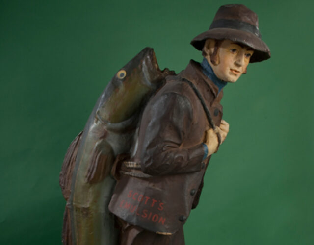 Figurine of a man in rain gear carrying large fish on his back