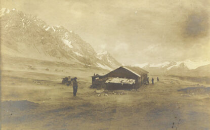 Old photograph of a worn cabin in arid mountains