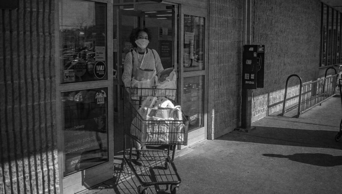 person with a mask on with a shopping cart at food store