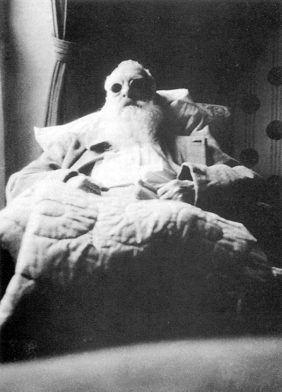 Black and white photo of man in bed wearing dark glasses