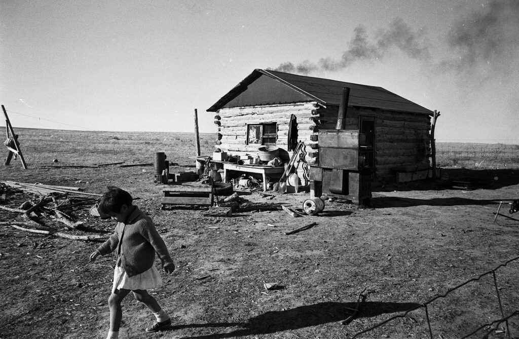 Black and white photo of young girl and impoverished home