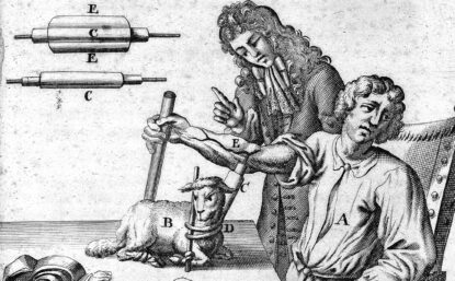 Engraving of a man at a table with another man standing next to him giving instruction. On the table is a small animal and a series of tools with letter labels.