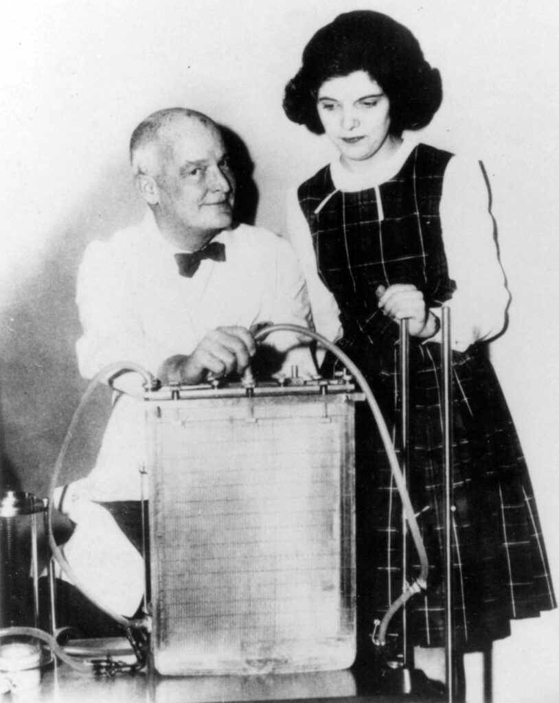 Black and white photo of older man in lab coat and younger woman 