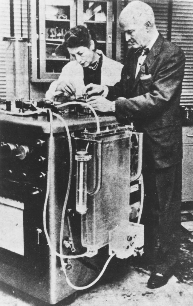 Black and white photo of man and woman examining large instrument