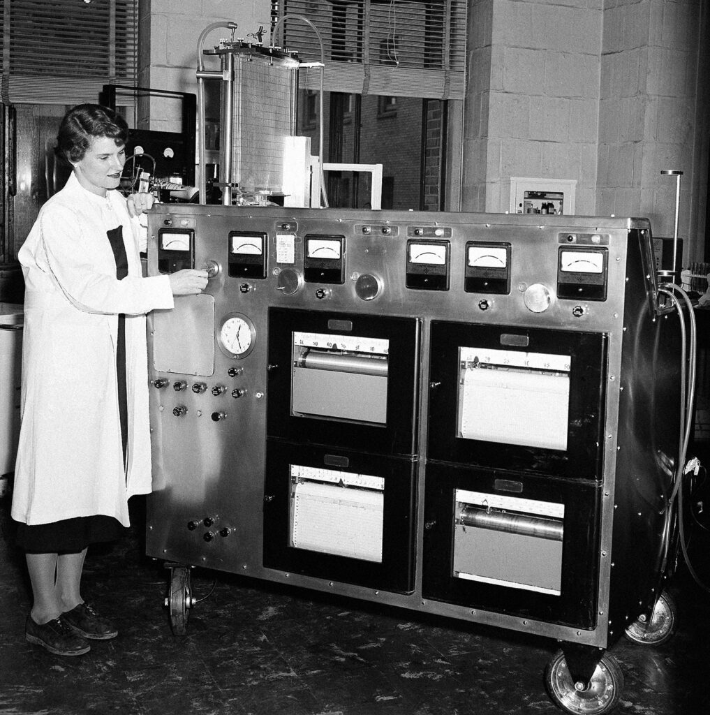 Photo of woman in lab coat in surgical room with large machine