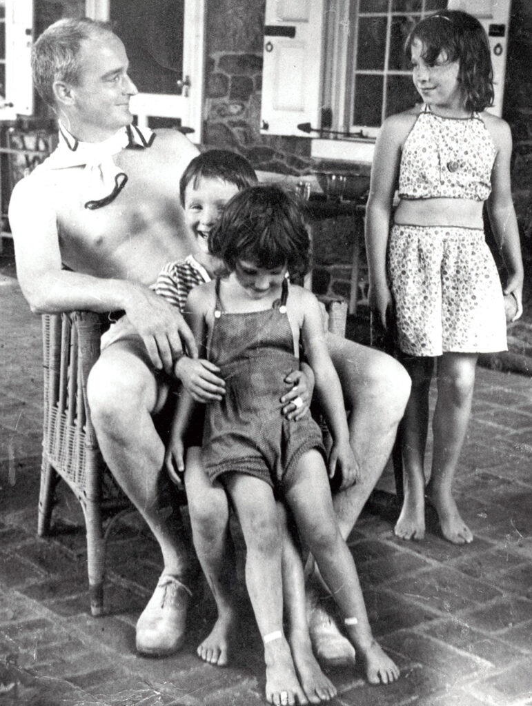 Photo of man relaxing with three young children outside