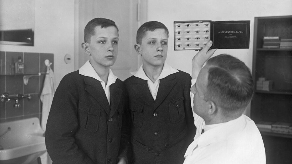 black and white photograph of a doctor examining twin boys