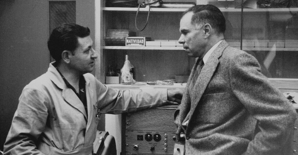 Black and white photo of two men talking in a lab
