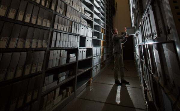 man standing among stacks of high shelves