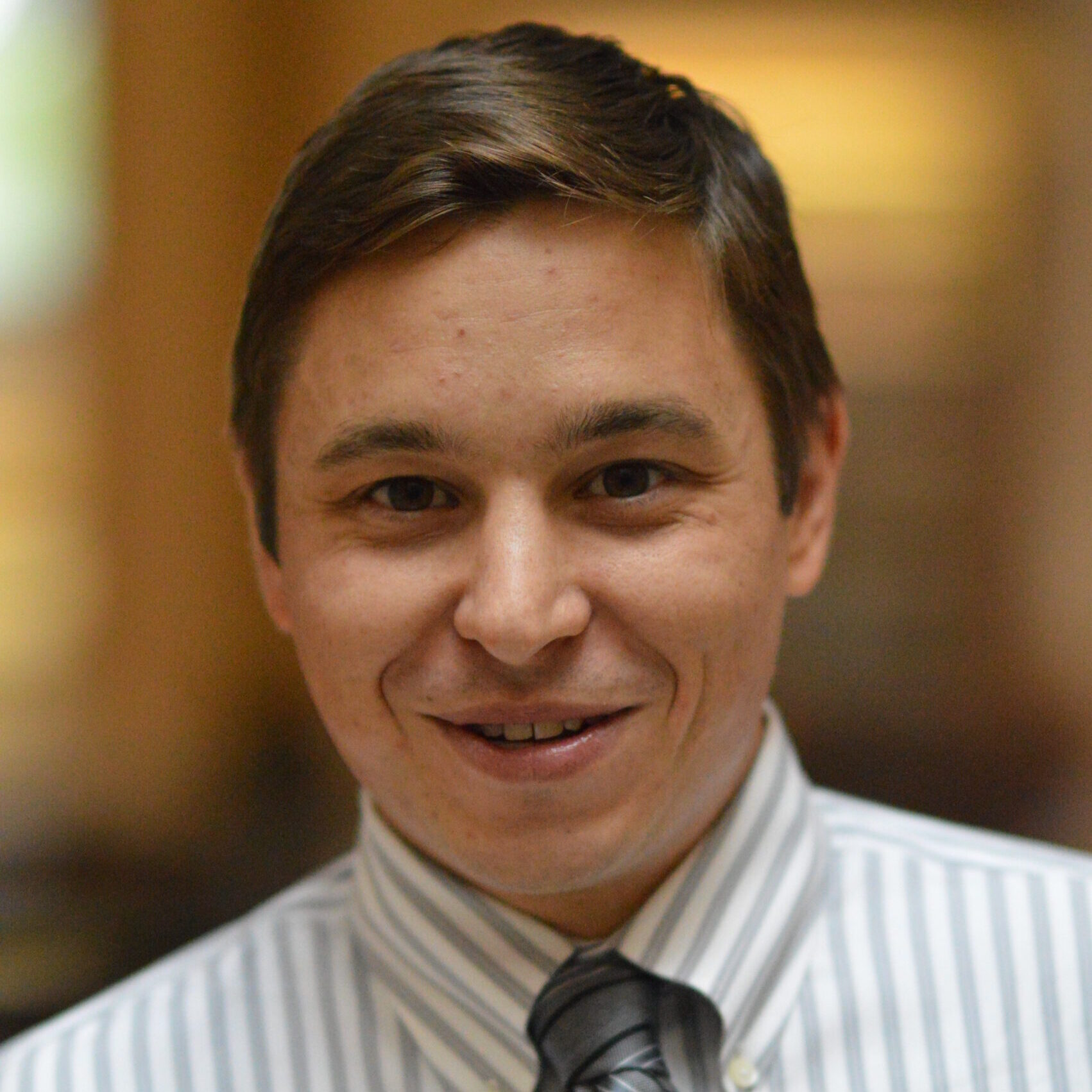 Josh in a striped shirt and tie, smiling