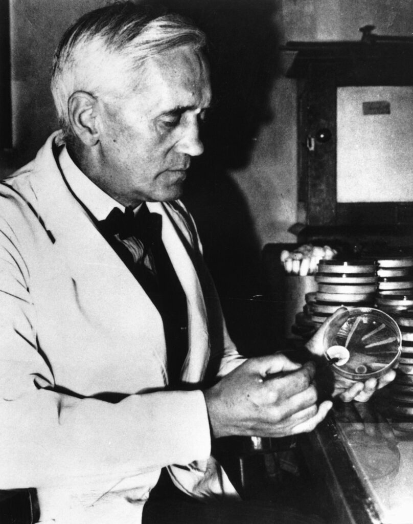 Alexander Fleming, holding a petri dish. 