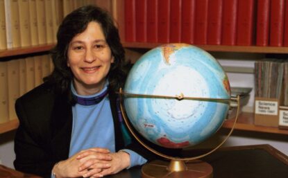 Susan Solomon in her NOAA office in Boulder, Colorado, next to a globe showing Antarctica. Courtesy National Oceanic and Atmospheric Administration.