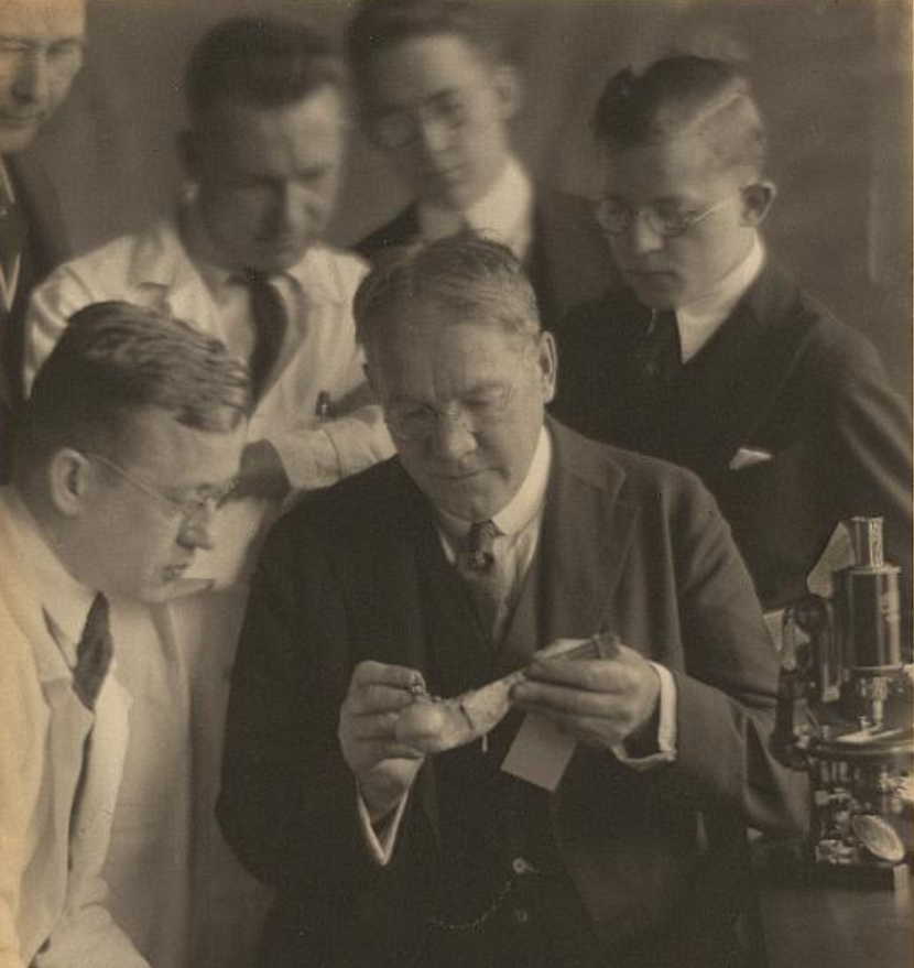 Photo of a group of men with a microscope