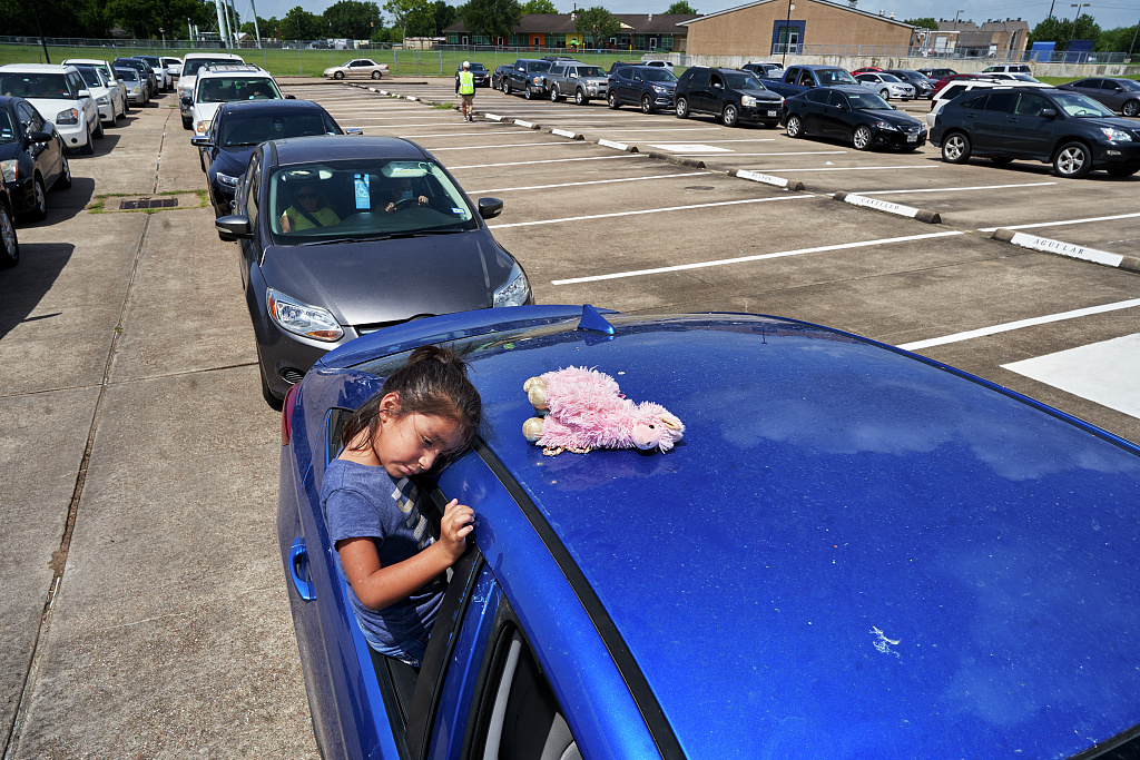 Color photo of girl resting in long line of cars