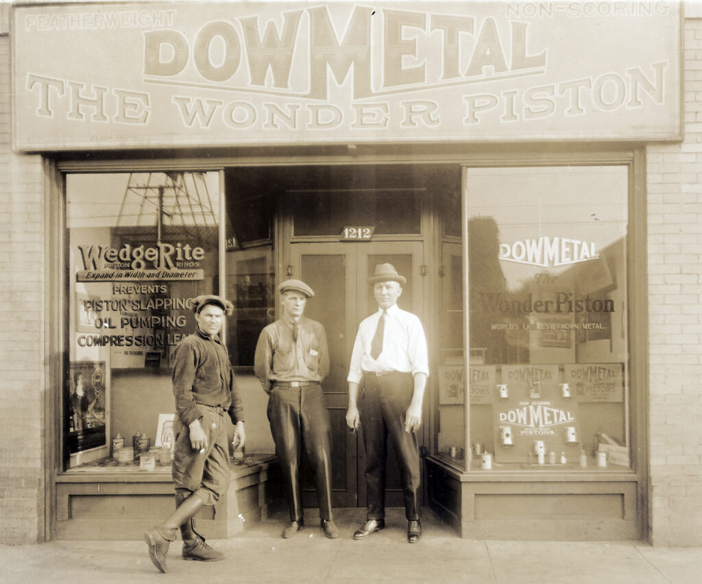Black and white photo of three men in front of a store