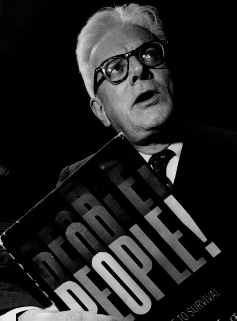 B/W photo of man in glasses holding a book