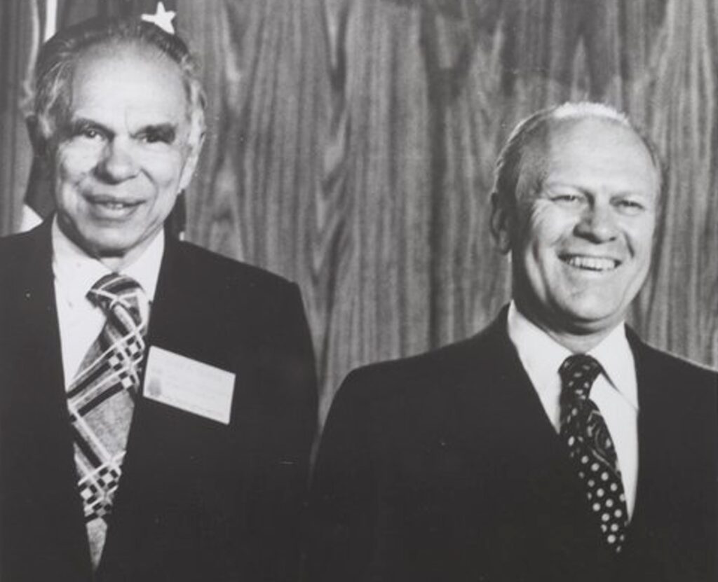 Glenn Seaborg and President Gerald Ford standing next to each other, laughing.