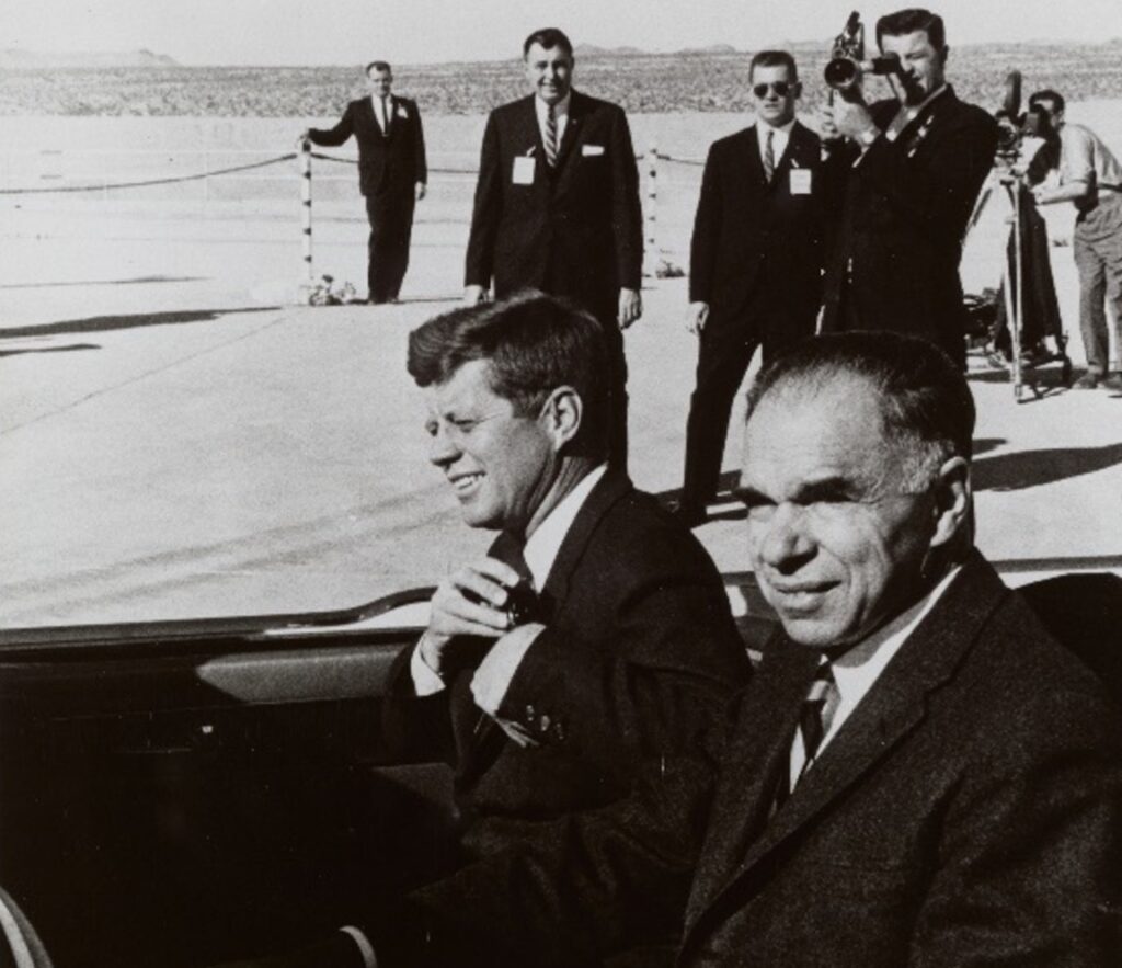 Seaborg and Kennedy at the Nevada Weapons Test Site, 1961, seated in a convertible car, wearing suits