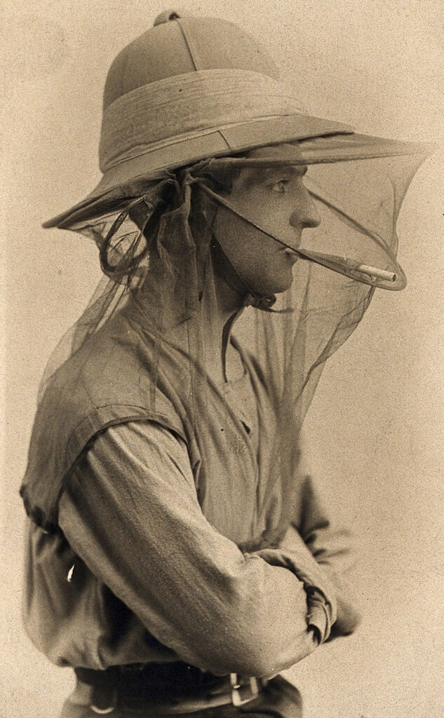 Black and white photo of man in pith helmet with net