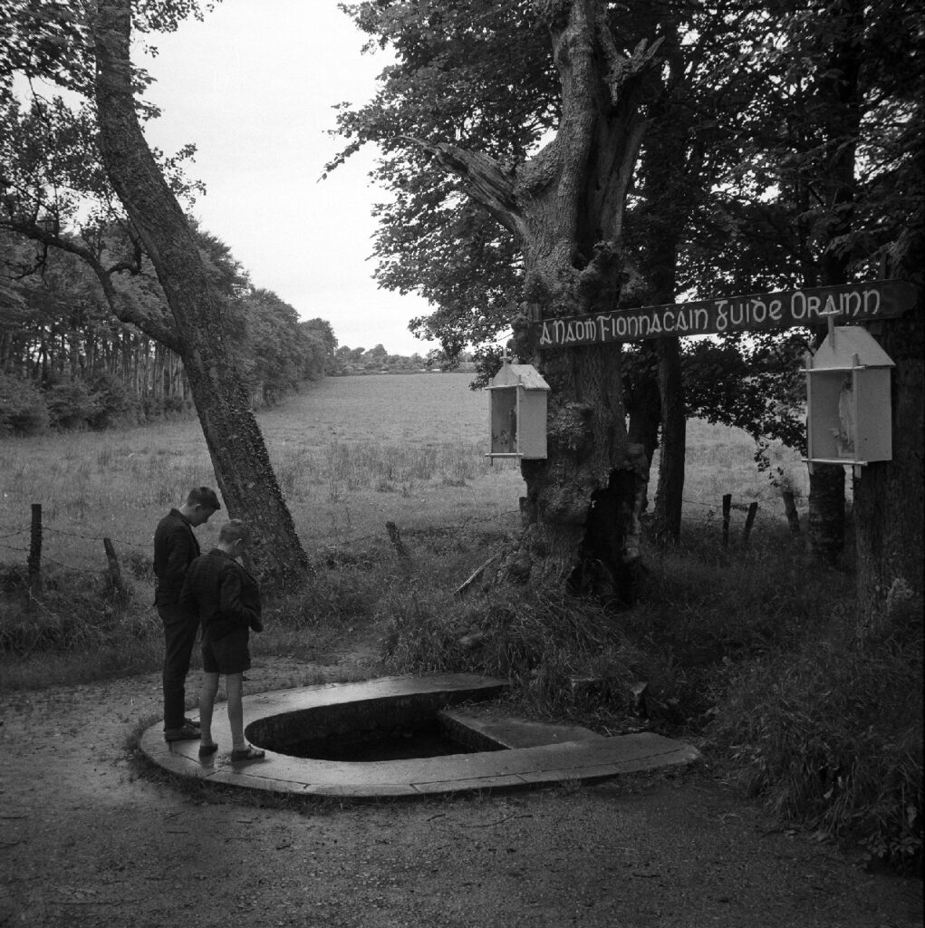 Black and white photo of boys in front of well