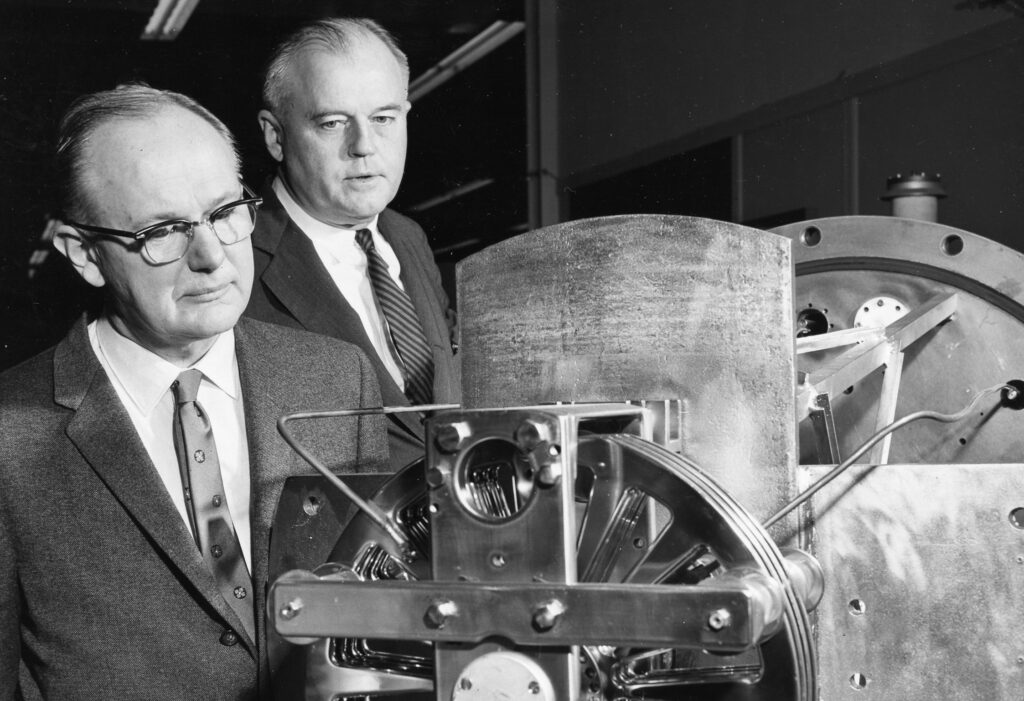 Black and white photo of two men looking at a machine