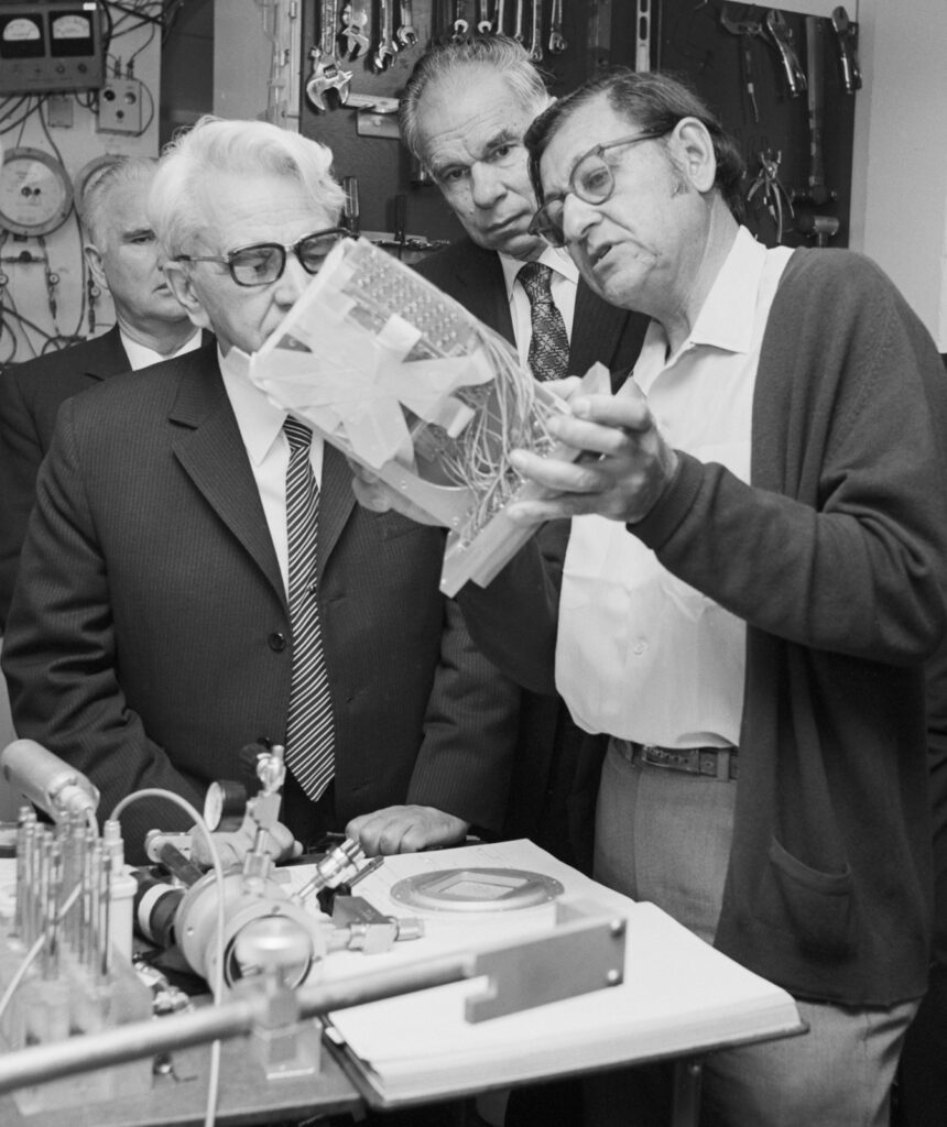 Photo of three men in a lab looking at an instrument