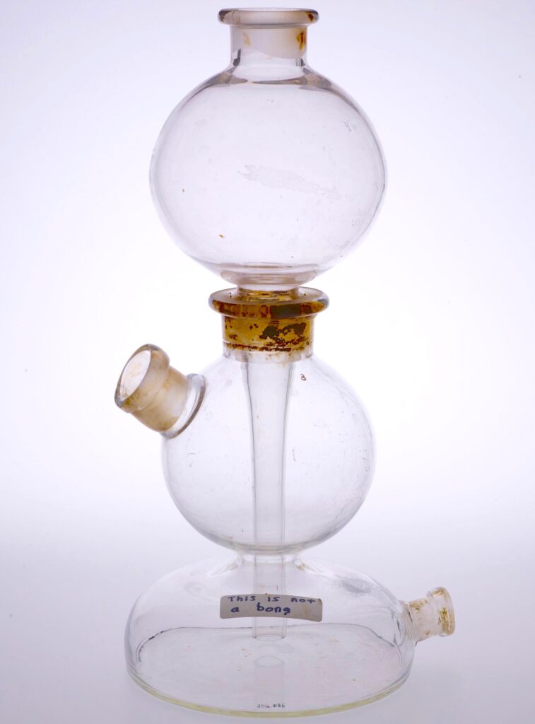 A glass vessel with three bulbous chambers. Each chamber has an opening. A handwritten label reads "This is not a bong"