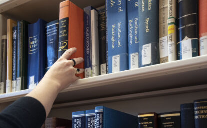 hand reaching for a book on a library shelf