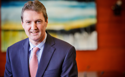 Photograph of Mark Stevenson in blue suit and red tie.