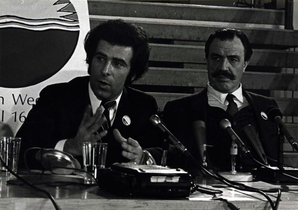 Two men seated at a table with microphones