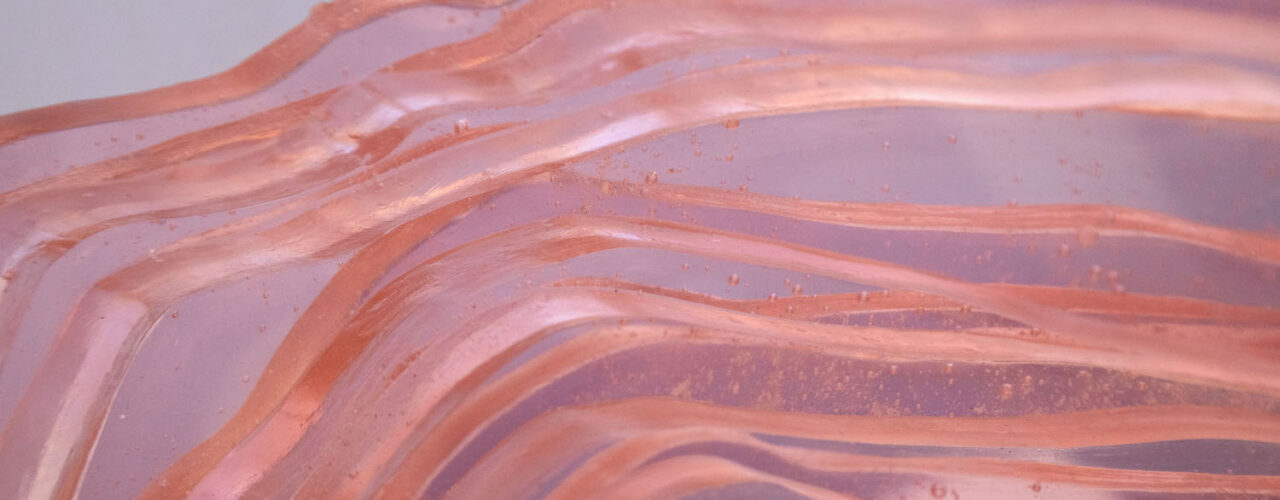 Detail of a pink translucent glass sculpture with wavy lines