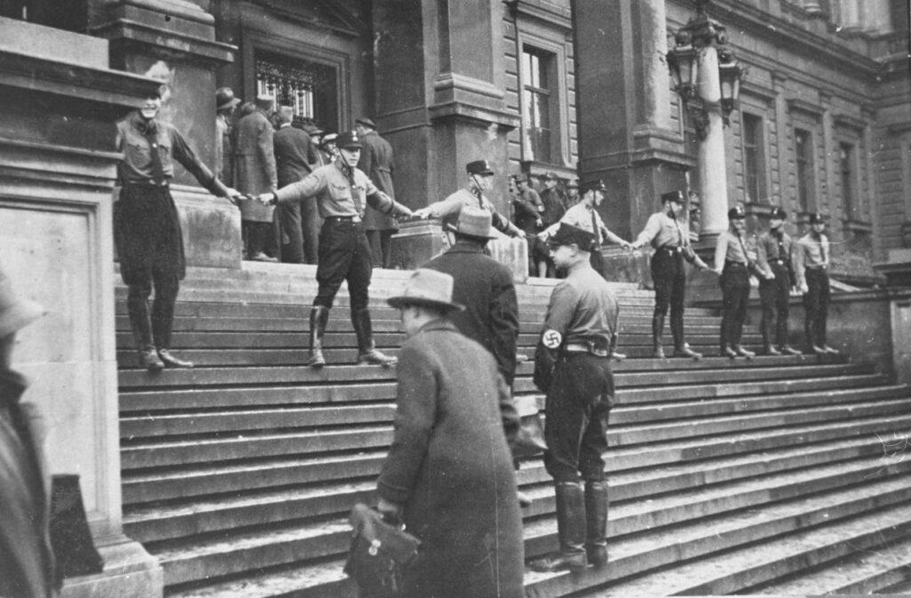 Uniformed men standing on building steps with arms interlocked