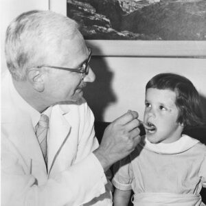 Albert Sabin demonstrates how the oral vaccine for polio is given to children.