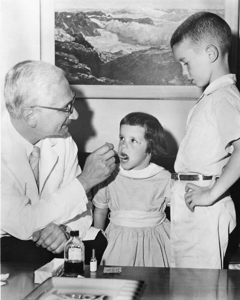 Albert Sabin demonstrates how the oral vaccine for polio is given to children. 