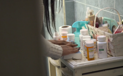 Photograph of a young woman's hands, putting pills from bottles into a pill sorter.