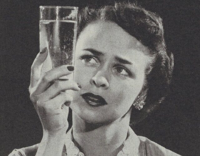 woman holding up a glass of water