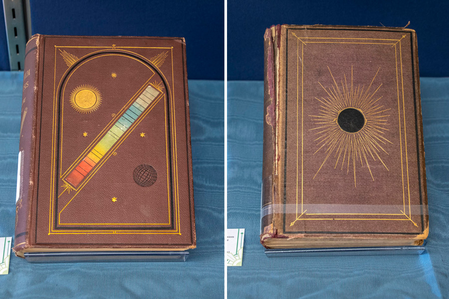 Two Spectrum Analysis books, bound in brown leather. One has a colorful spectrum and illustration of a sun. The other has a solar eclipse