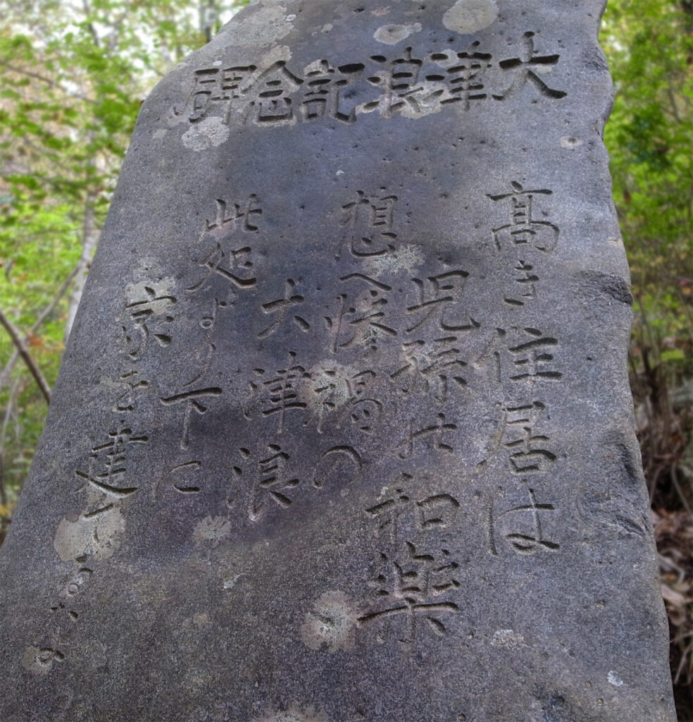 Detail of a weathered stone marker with Japanese inscription