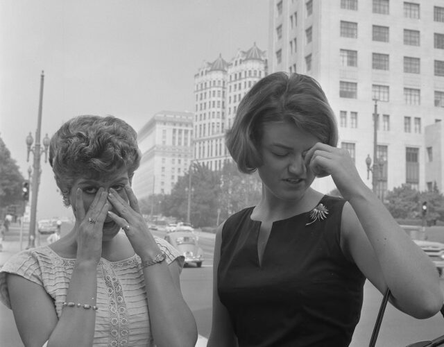 Two women standing on street dabbing their eyes