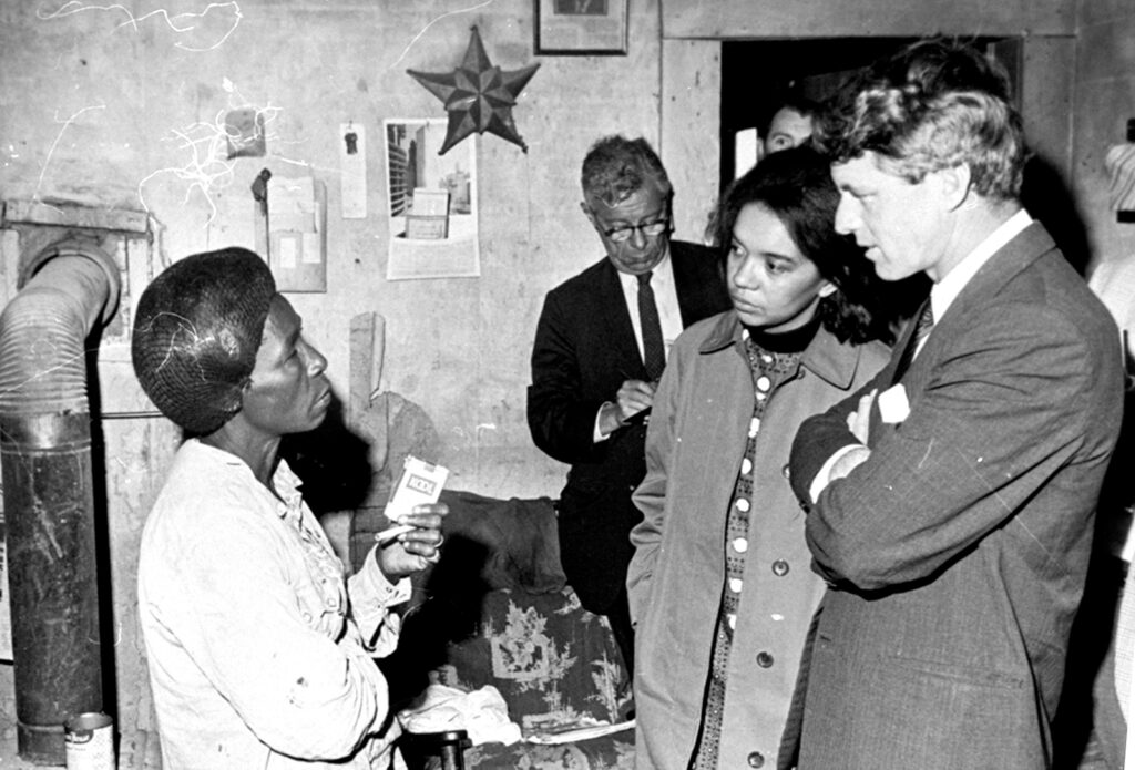 Black and white photo of people talking inside a home