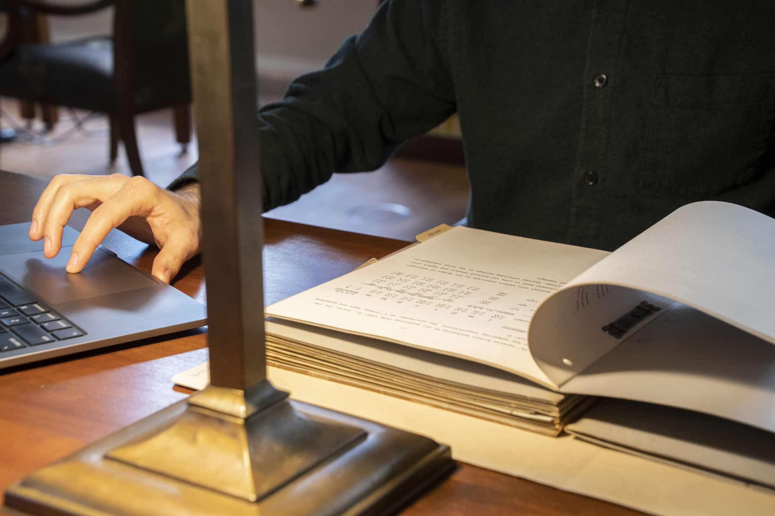 View of hands working on a laptop with library book