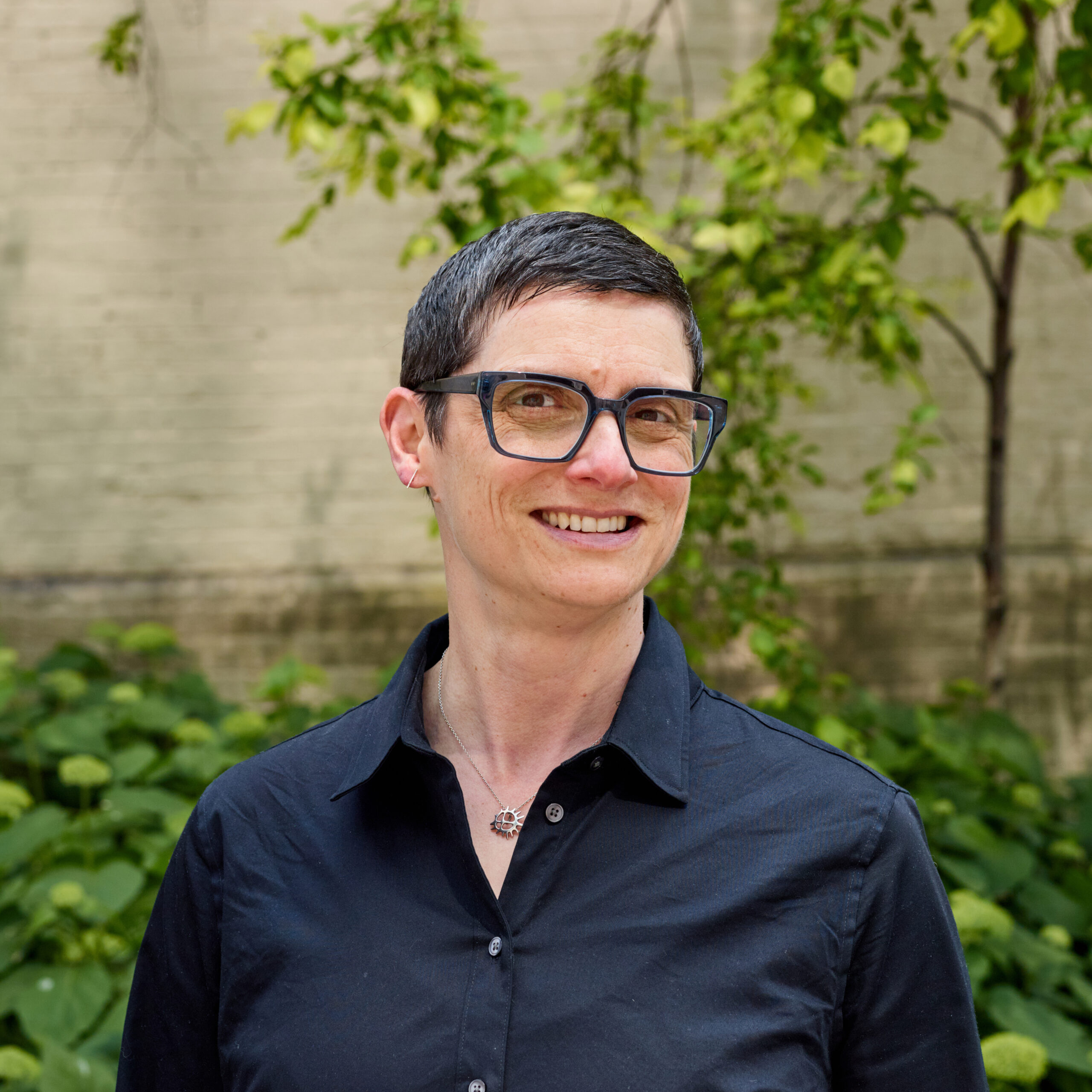 Christy, outdoors, smiling, wearing glasses, pendant, navy button down shirt