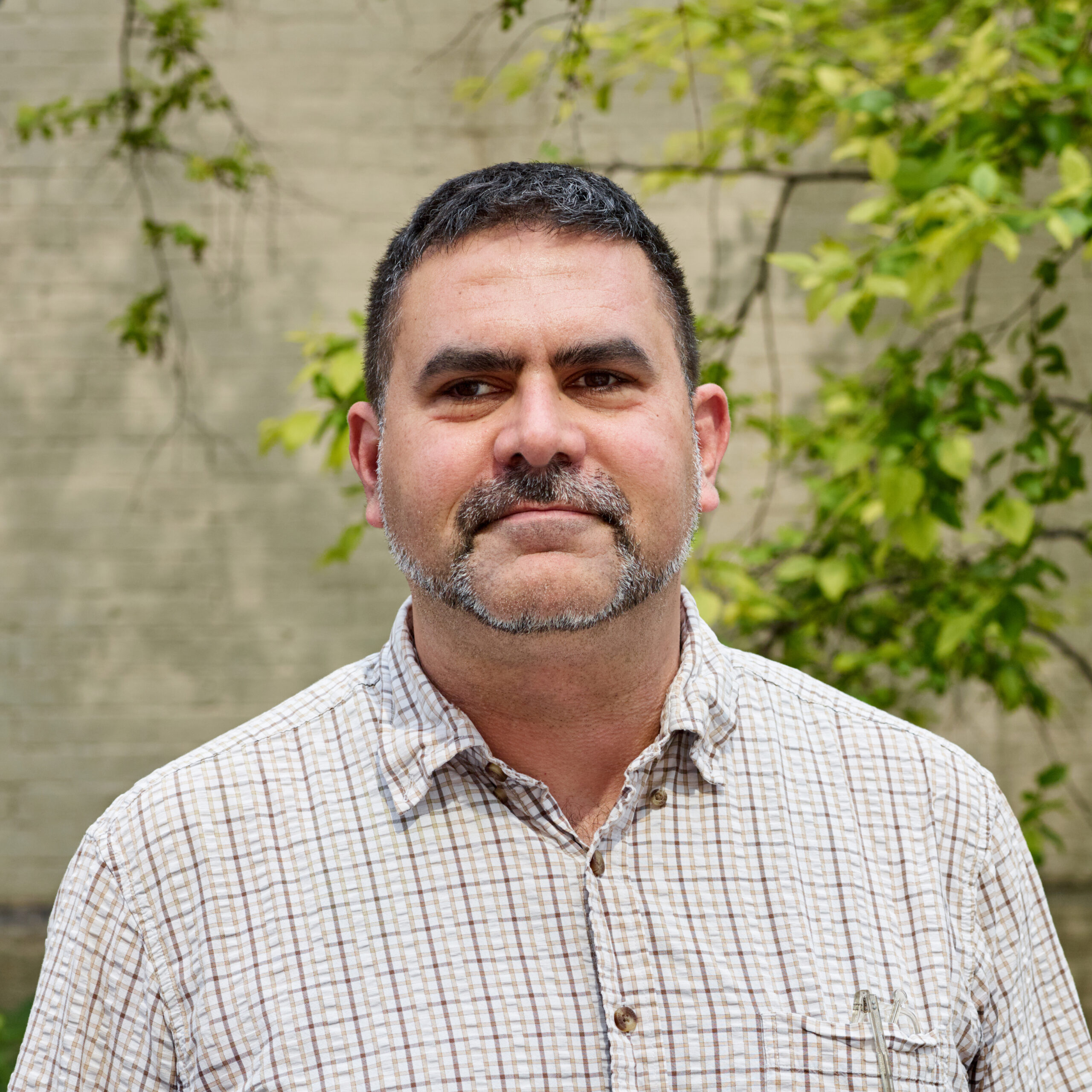 Eddie outdoors wearing a checked light-colored button-down shirt