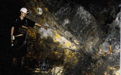 A man wearing a helmet and flashlight points to a natural nuclear reactor inside a cave in Gabon, Africa.