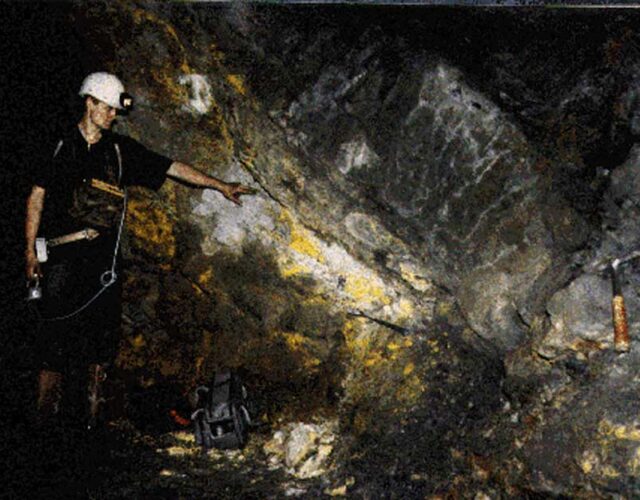 A man wearing a helmet and flashlight points to a natural nuclear reactor inside a cave in Gabon, Africa.