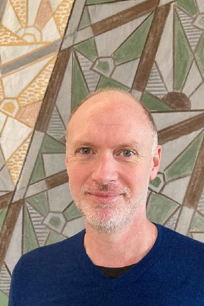 Jim Porter in royal blue shirt in front of an abstract pattern design