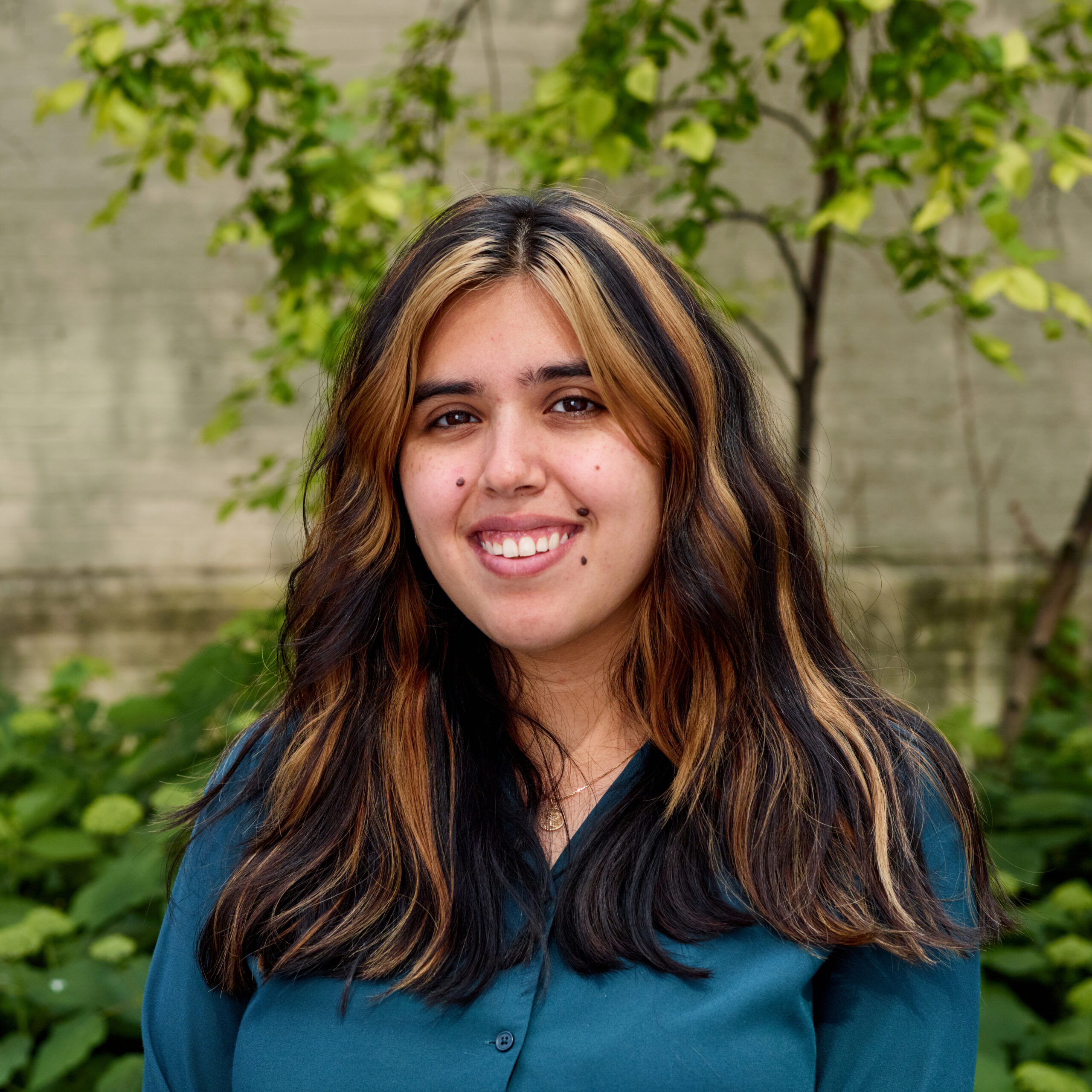 Juliette outdoors, smiling, wearing a blue button-down shirt