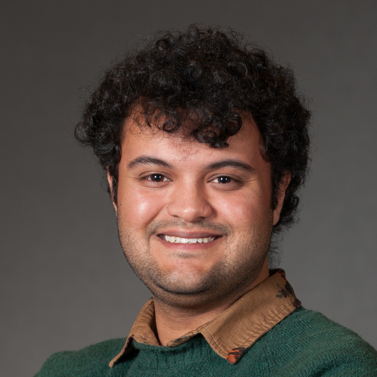 Nikhil Joseph Dharan in green sweater over tan collared corduroy shirt