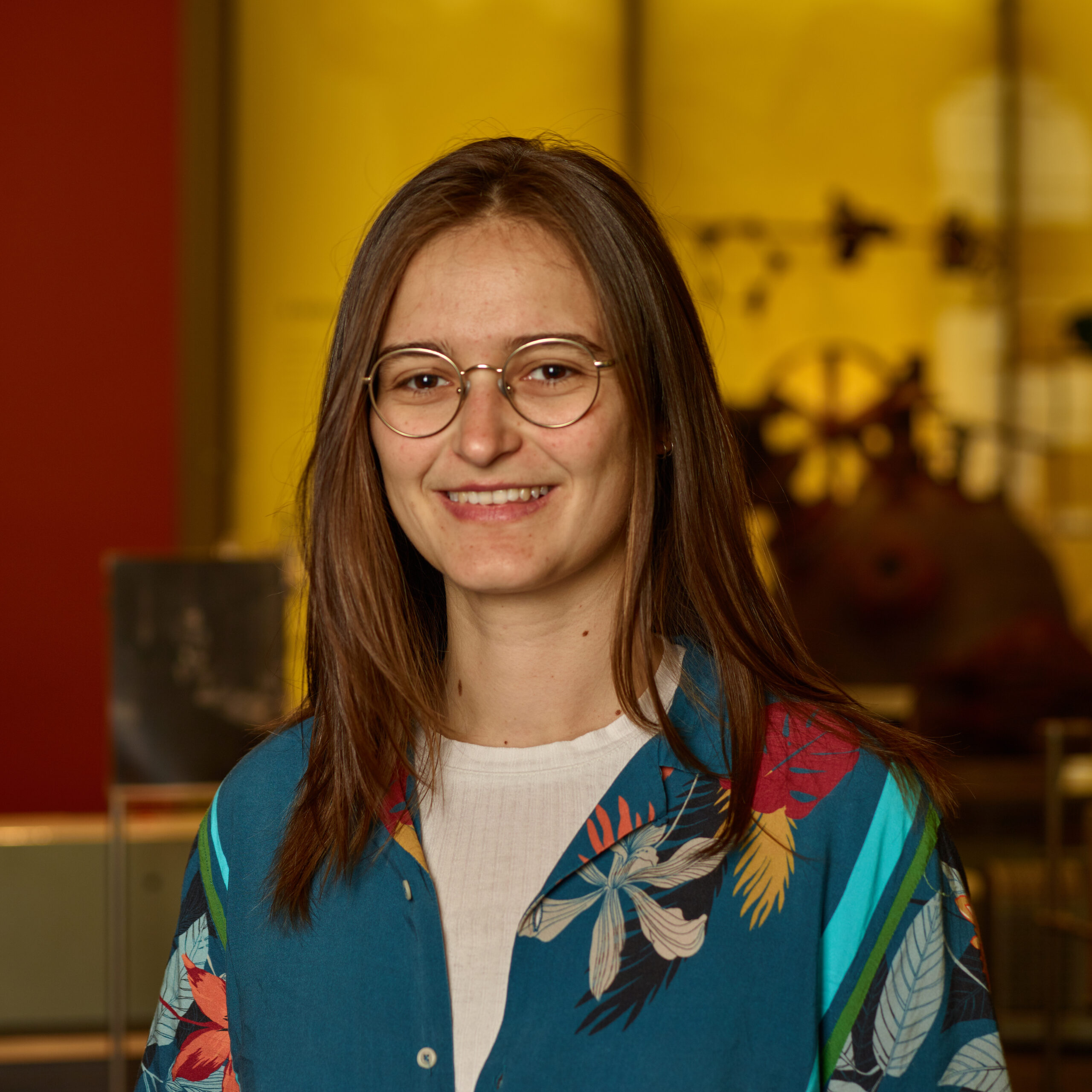 Sarah in museum wearing glasses and colorful top