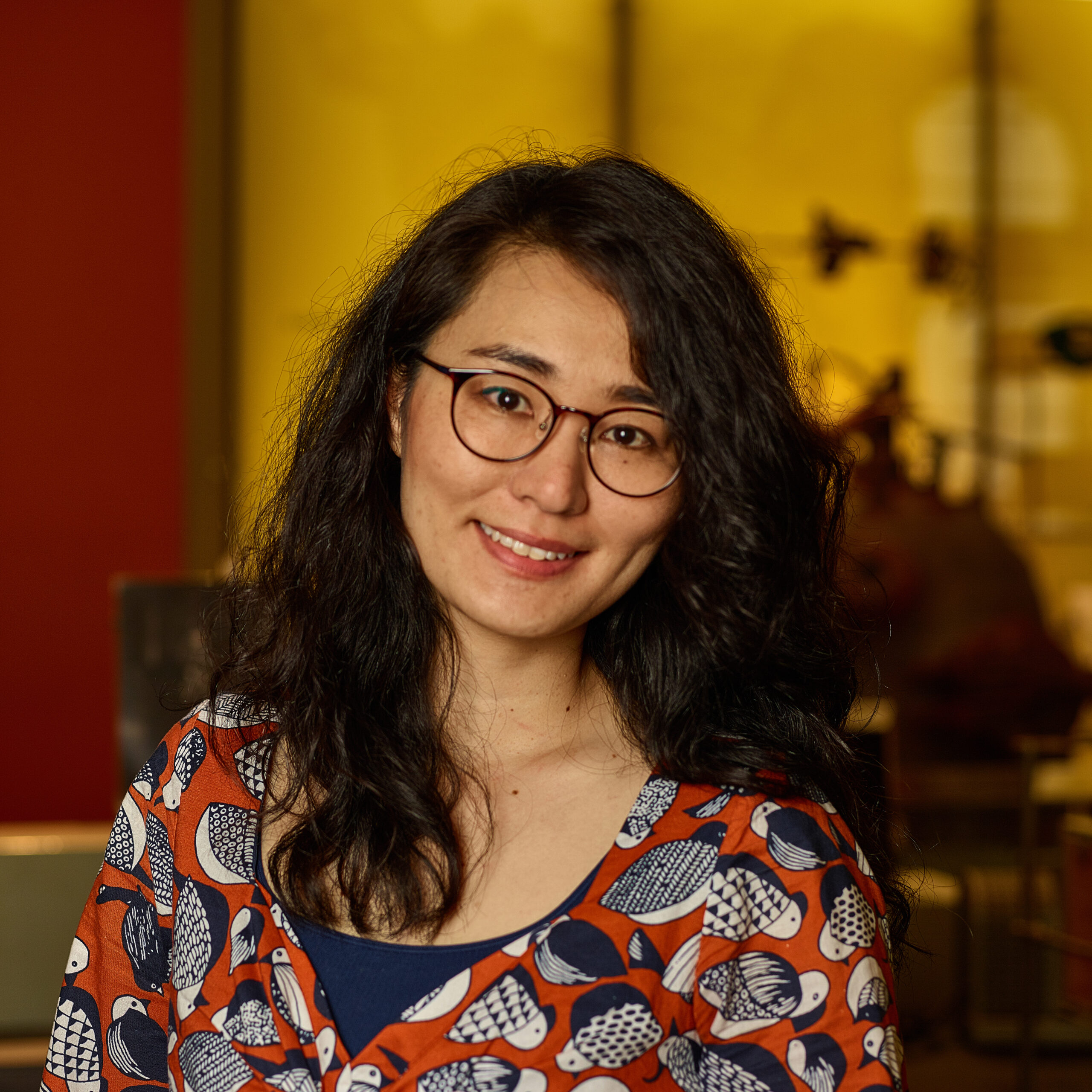 Shuko in museum, wearing glasses and a shirt with a bird pattern